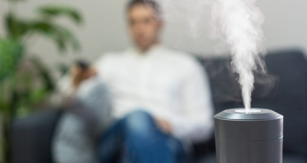 Air humidifier at living room. Man watching tv on the background.