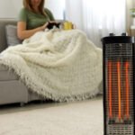 Woman with cat at home, focus on electric halogen heater